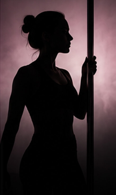 Trainerin an der Pole als dunkle Silhoute im Profil.
